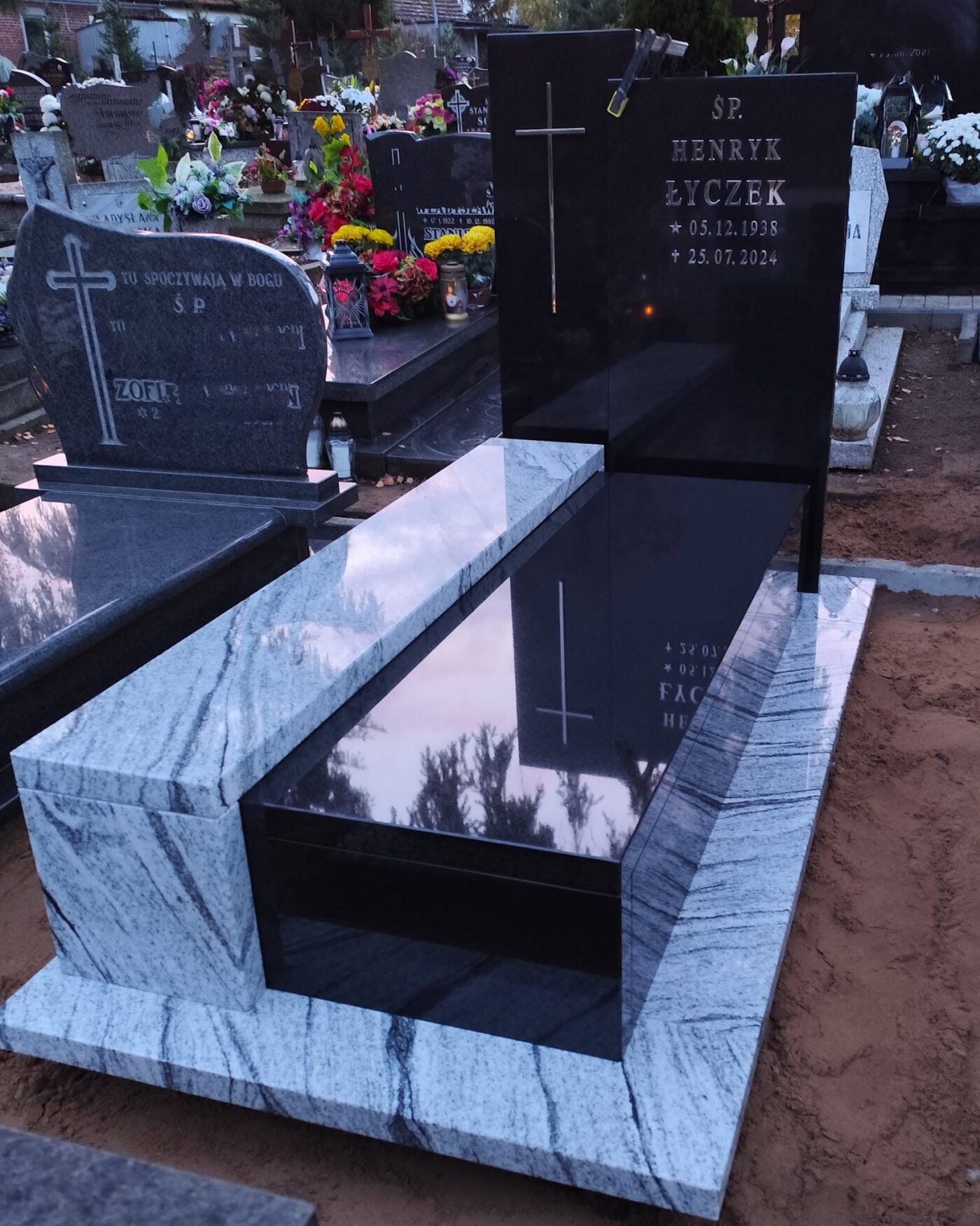 Nowoczesny pomnik łączący czarny polerowany granit z jasnym Viscont White, fotografowany o zmierzchu